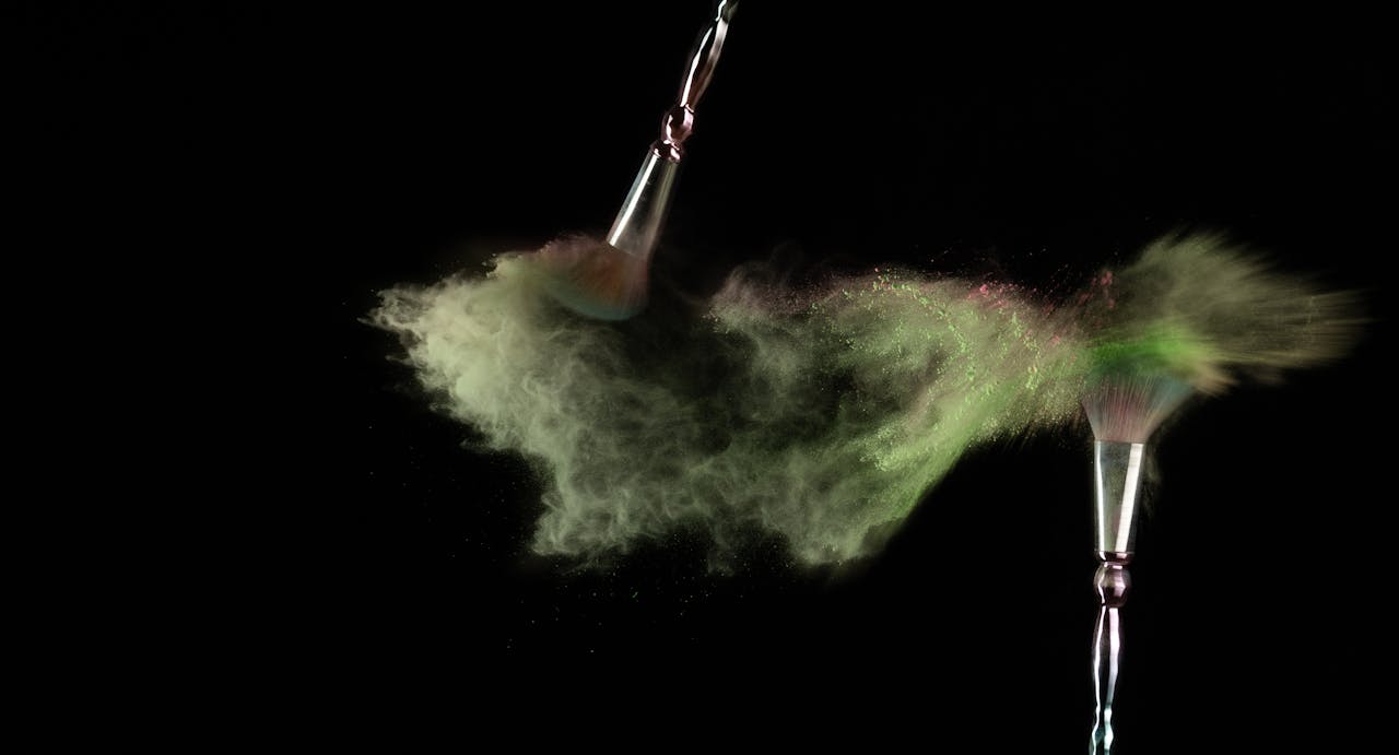 Vibrant explosion of colorful makeup powder from brushes on black background.